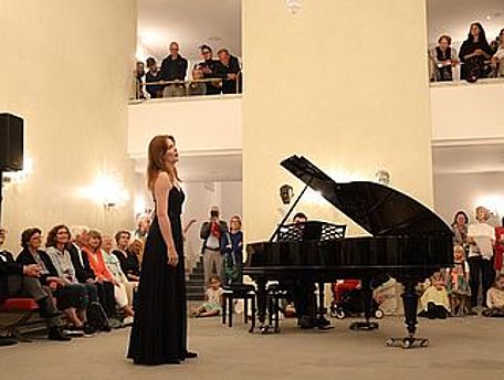 Eine Frau steht vor einem Piano und singt